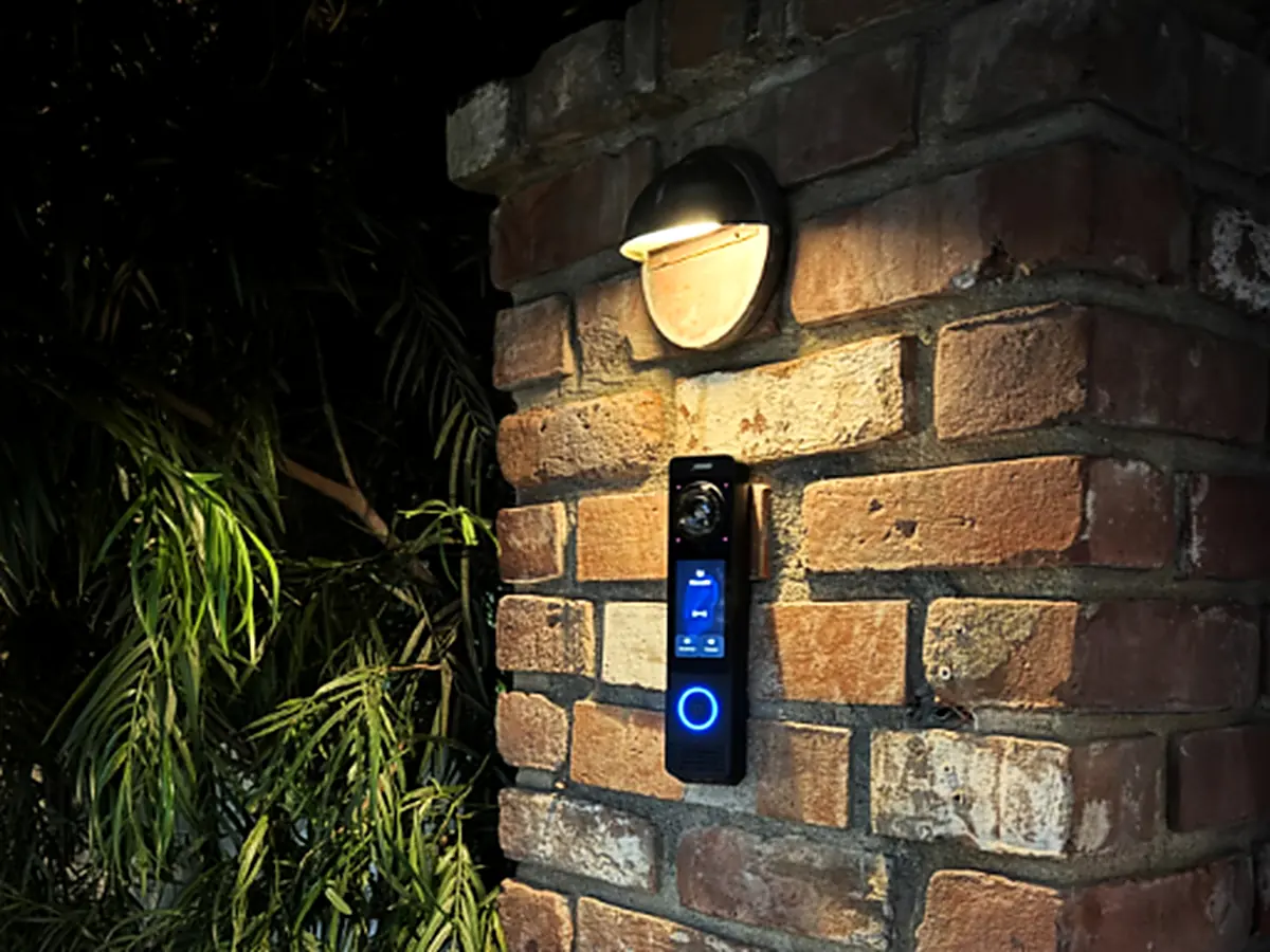 Access control reader and video intercom mounted beside an entry at night