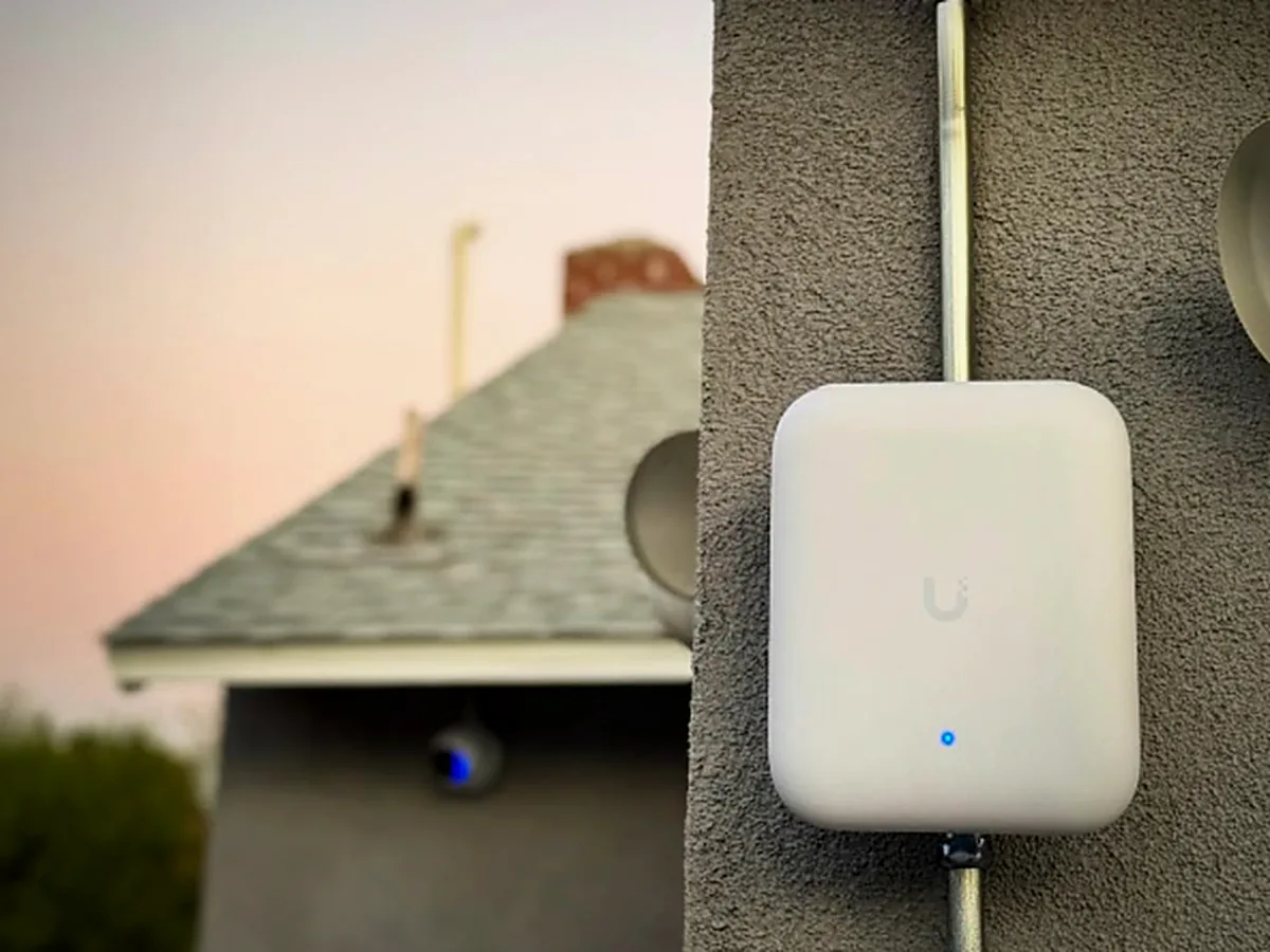 Ubiquiti UniFi access point mounted on an exterior wall at dusk
